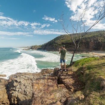 Ung mand tager billeder af kyststrækning i Noosa National Park, Queensland