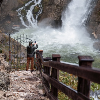 Mand tager billede af Savica-vandfaldet i Triglav National Park om efteråret, Slovenien