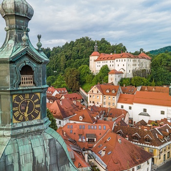 Skofja Loka by med kirketårnet i front og Skofja Loka Slot i baggrunden, Slovenien