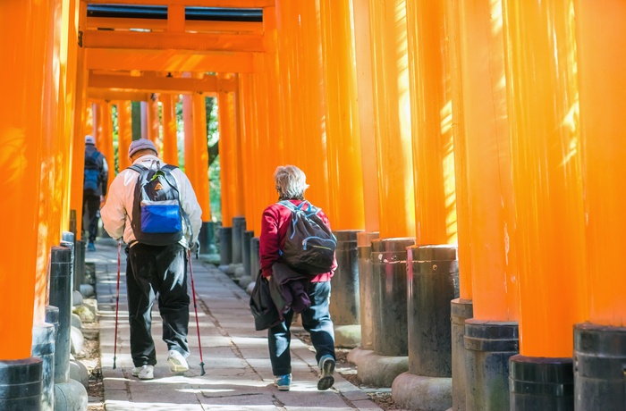 Ældre par på vej gennem torri portene i Fushimi Inari-helligdommen, Kyoto i Japan 