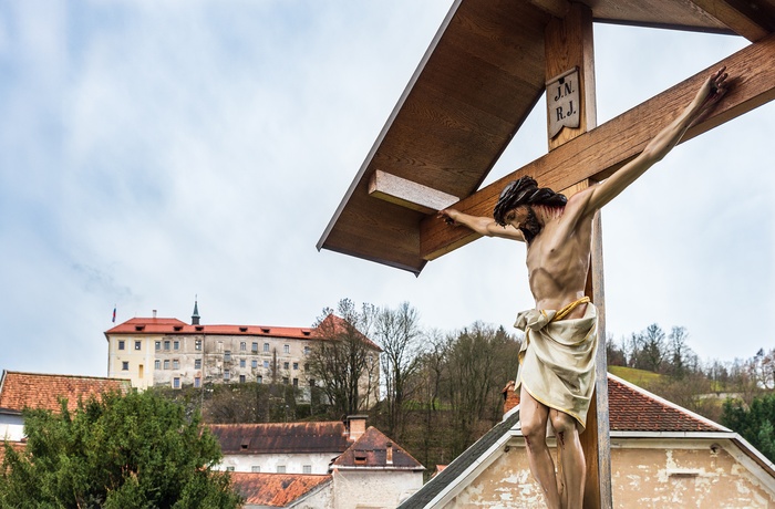 Træudskæring af Jesus på kors og Skofja Loke Slot og Museum i baggrunden, Slovenien