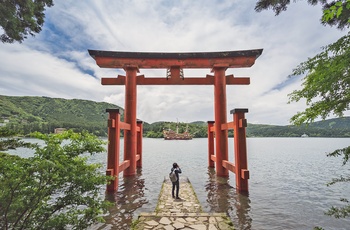 Turist tager billeder under en torri gate ved bredden af Lake Ashi med Mt. Fuji i baggrunden, Japan 